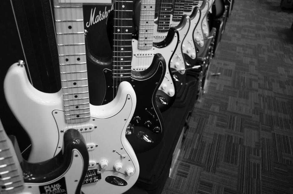 A bunch of guitars laid set-up in a guitar shop.