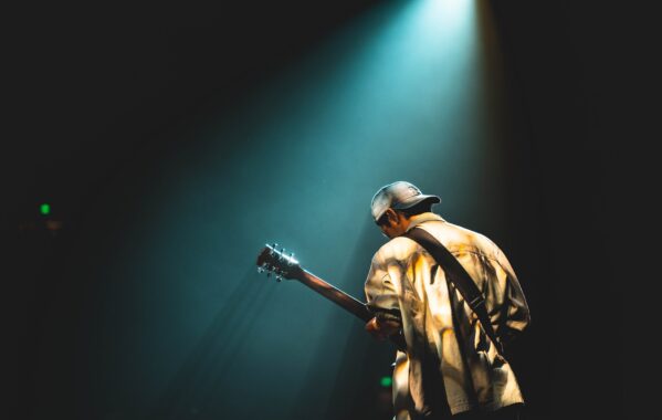 Someone playing their guitar on stage.